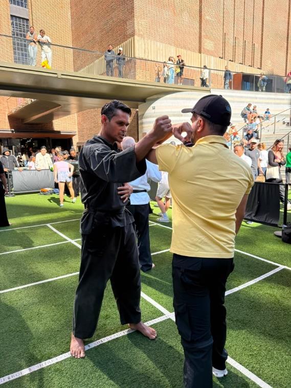 A coach guiding a member of the public through a self-defence move at the CelebrAsia workshop